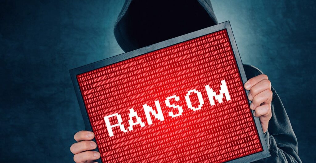 Person in hooded sweatshirt holding picture with the word ransom on it
